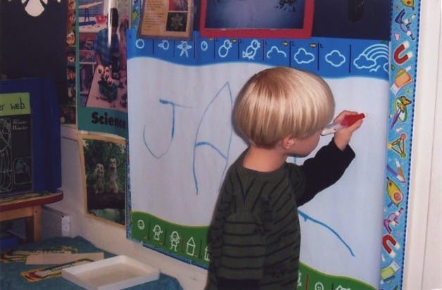 Child drawing on a whiteboard in a classroom