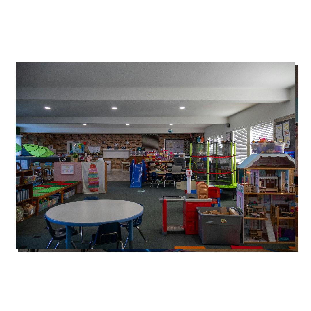 Playroom featuring tables, a slide, a small trampoline, and a toy dollhouse