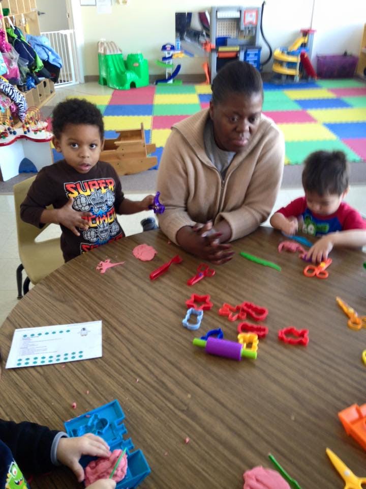 Adult and two children playing with modeling clay at a table