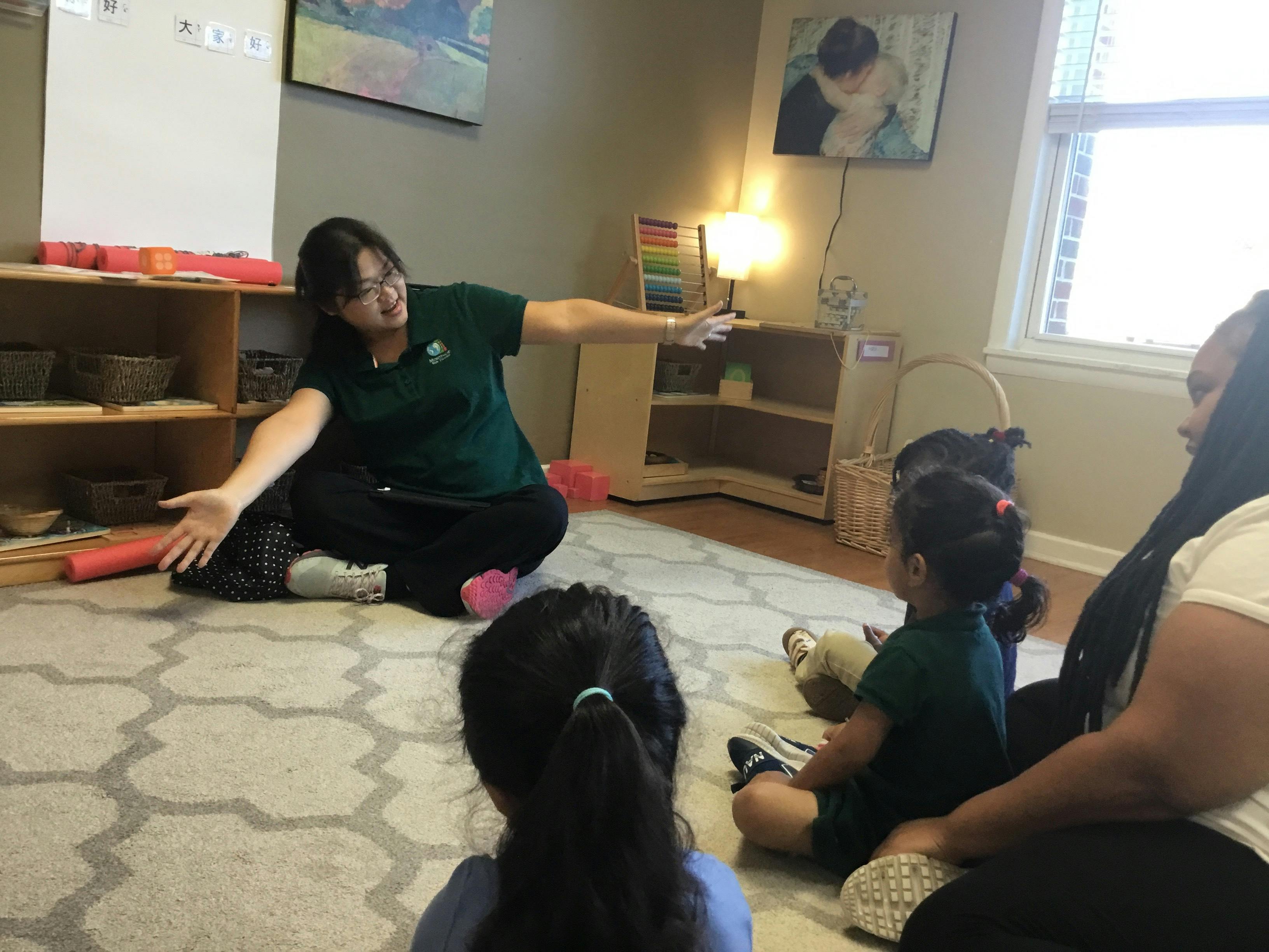 Adult leading a group of children in an activity on the floor