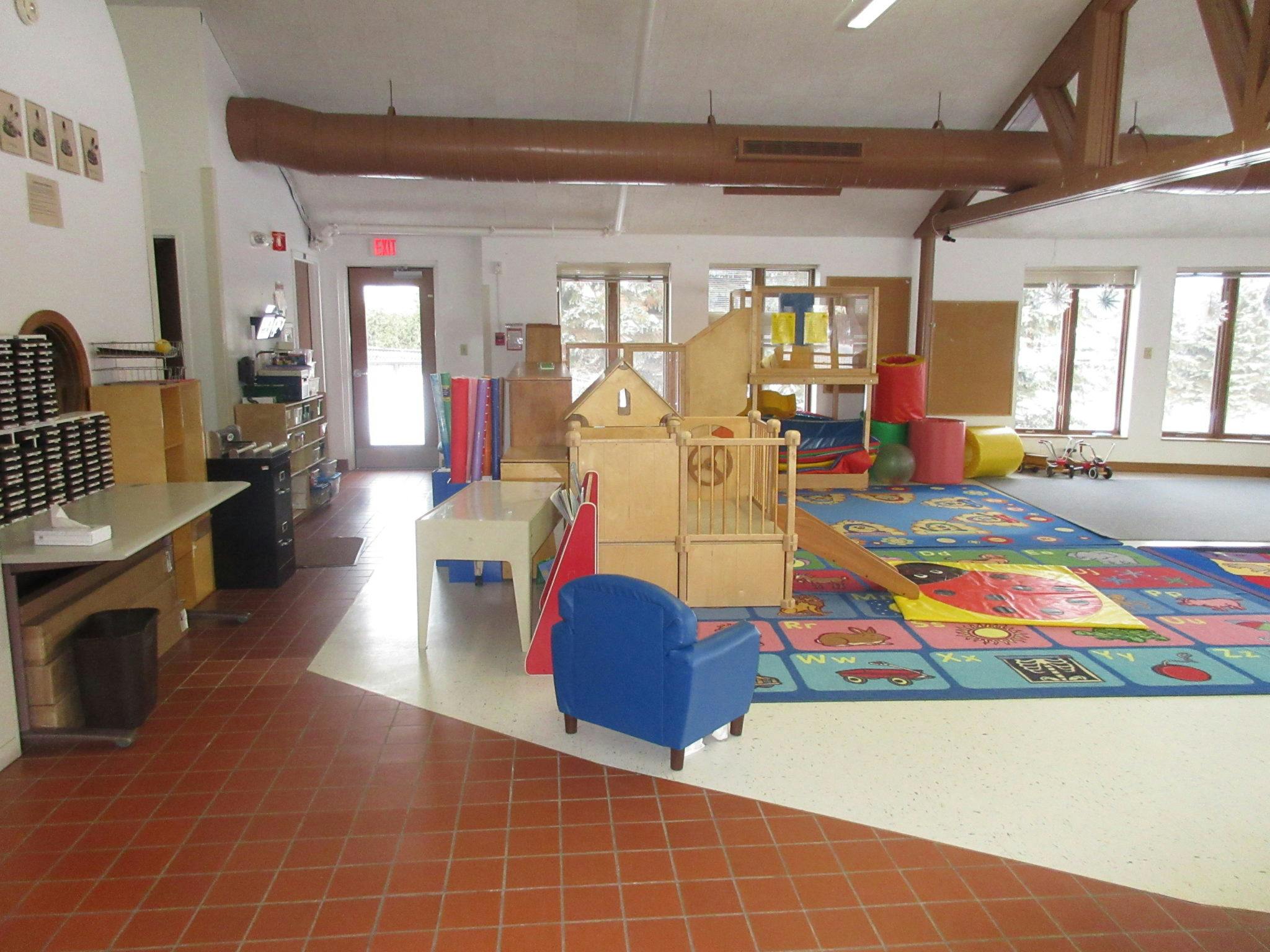 Playroom with a colorful rug, play structures, and a blue chair