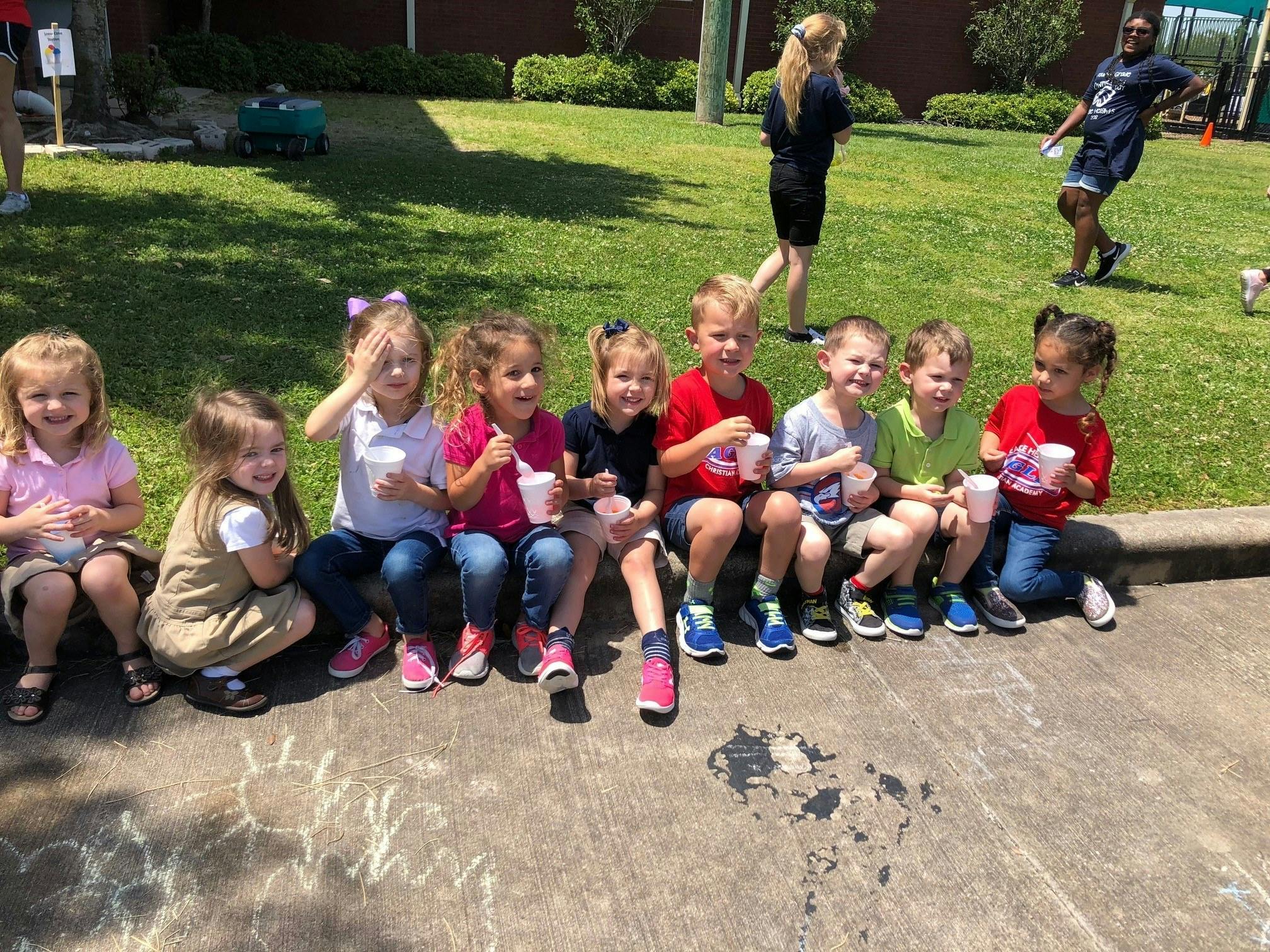 Group of children sitting on a curb holding cups