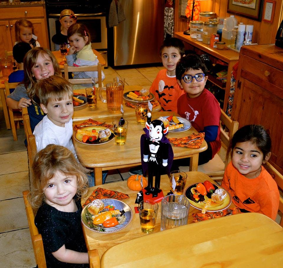 Children sitting at tables with plates of food and drinks