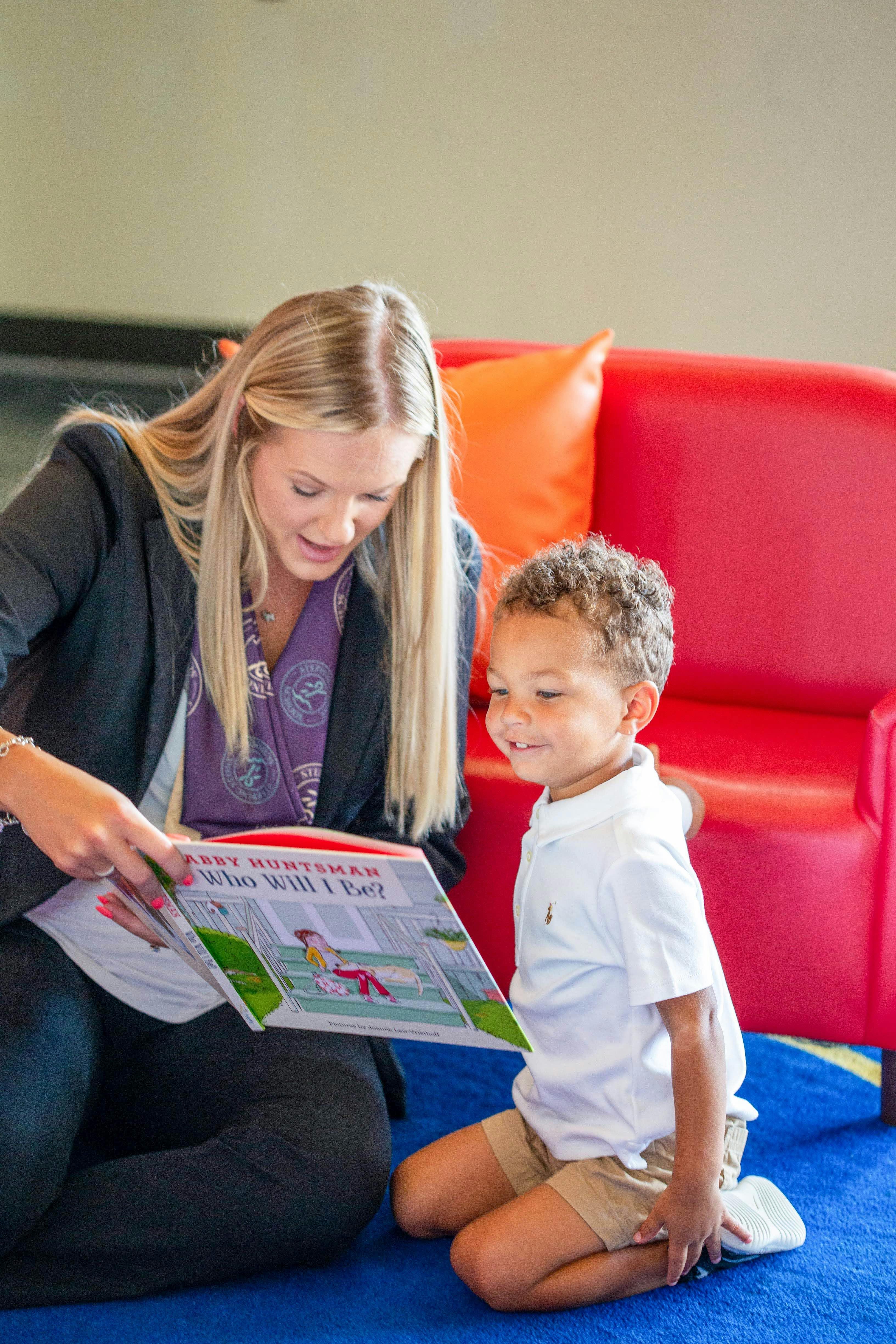 Person kneeling and reading a book to a child, Who Will I Be?