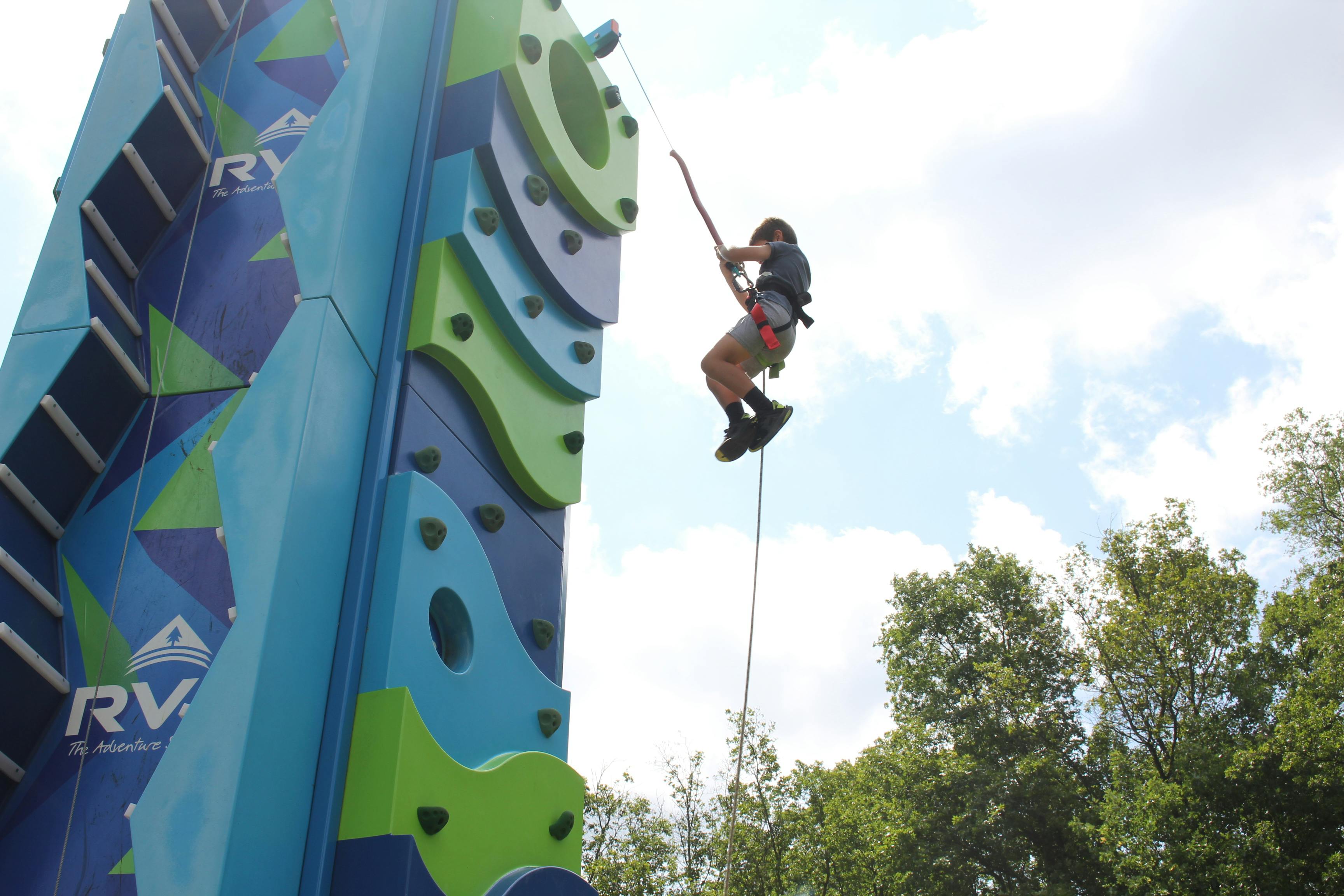 Person rappelling down a climbing wall