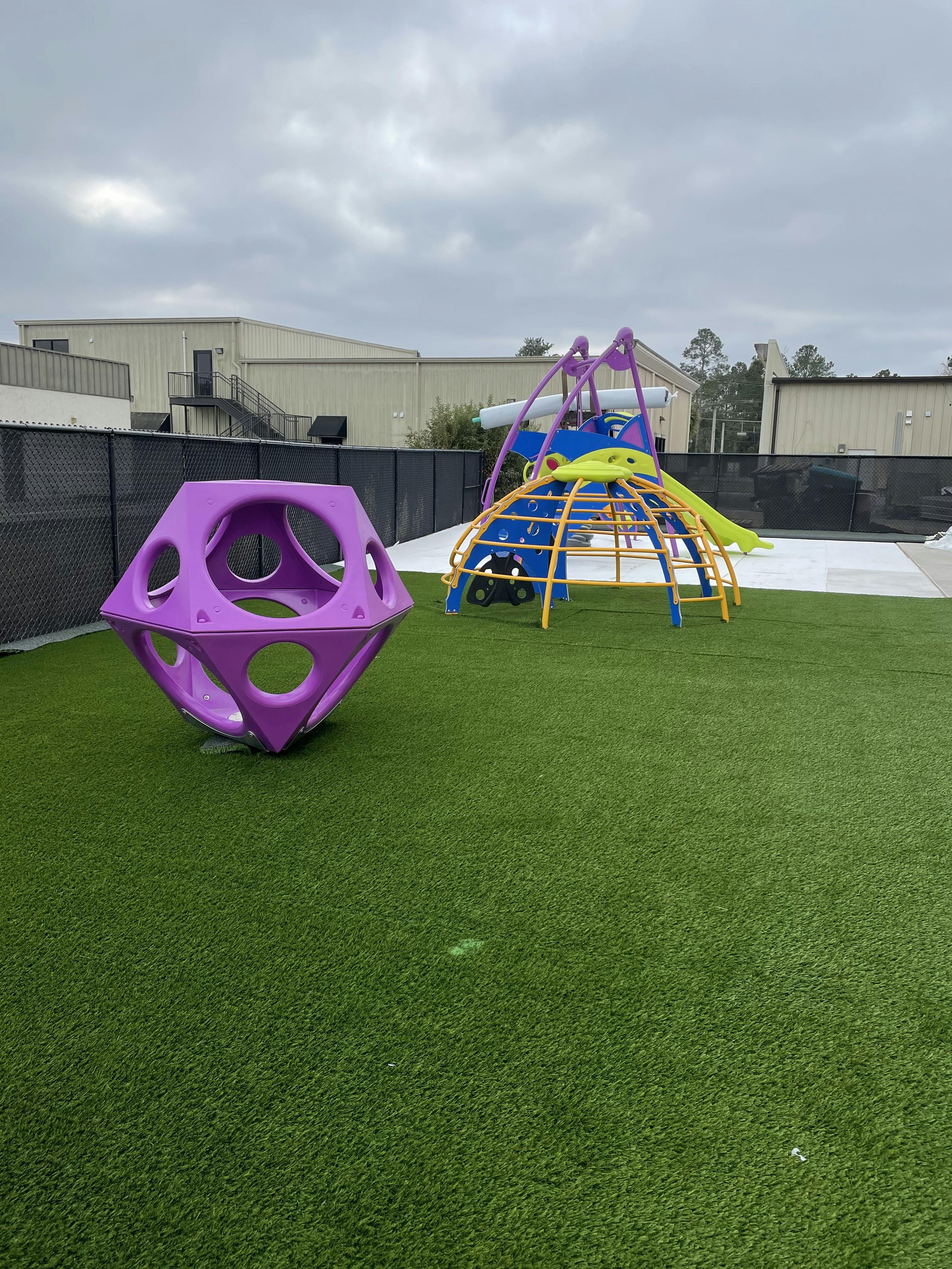 A purple geometric climbing structure and a colorful playground set with slides