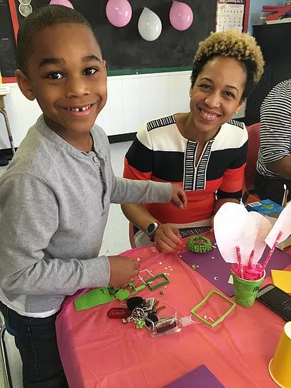 Child and person smiling while crafting at a table