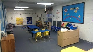 Classroom with small tables and chairs, bulletin board, and storage units