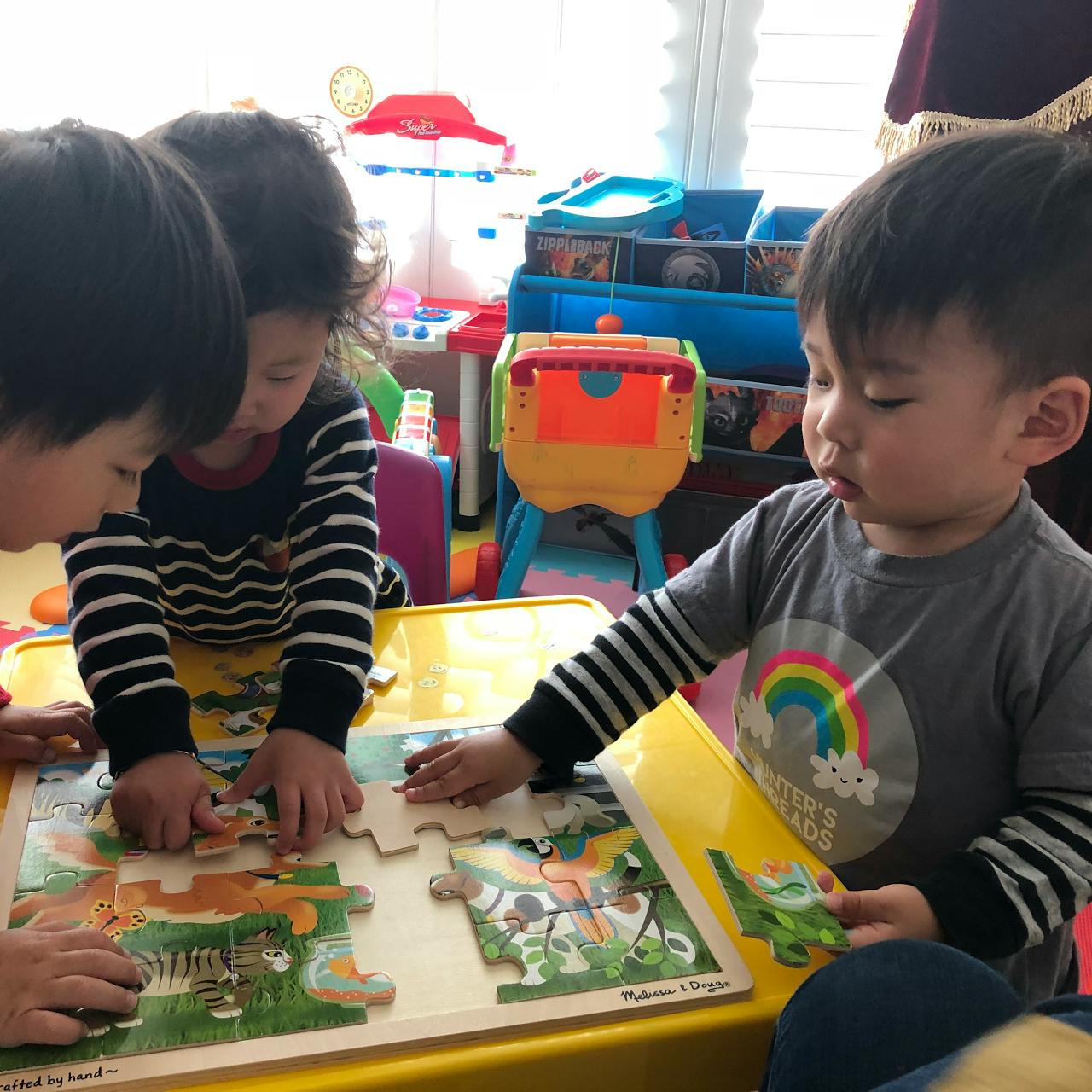 Three children assembling a floor puzzle