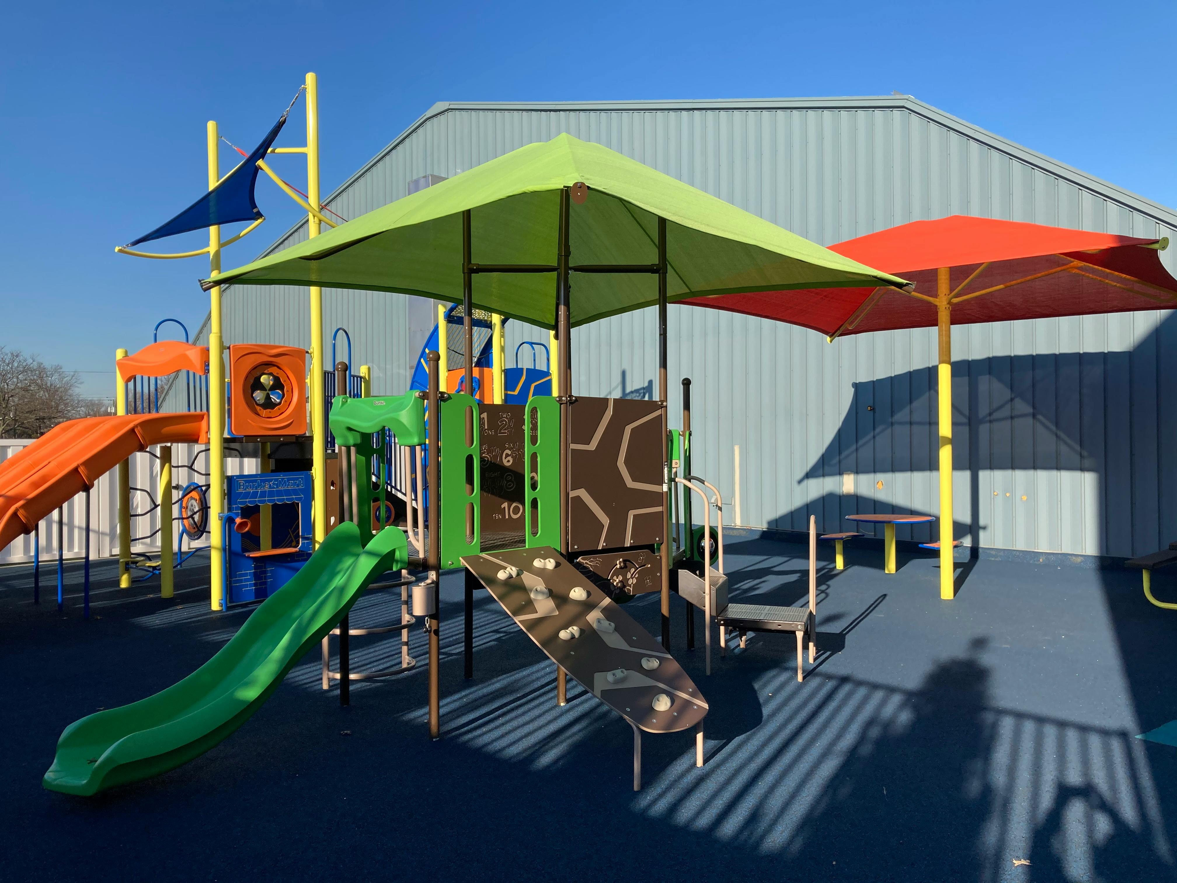 Playground with slides, climbing structures, and shade umbrellas