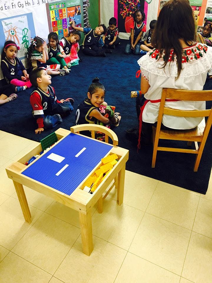 Adult sitting on chair facing children sitting on floor in classroom