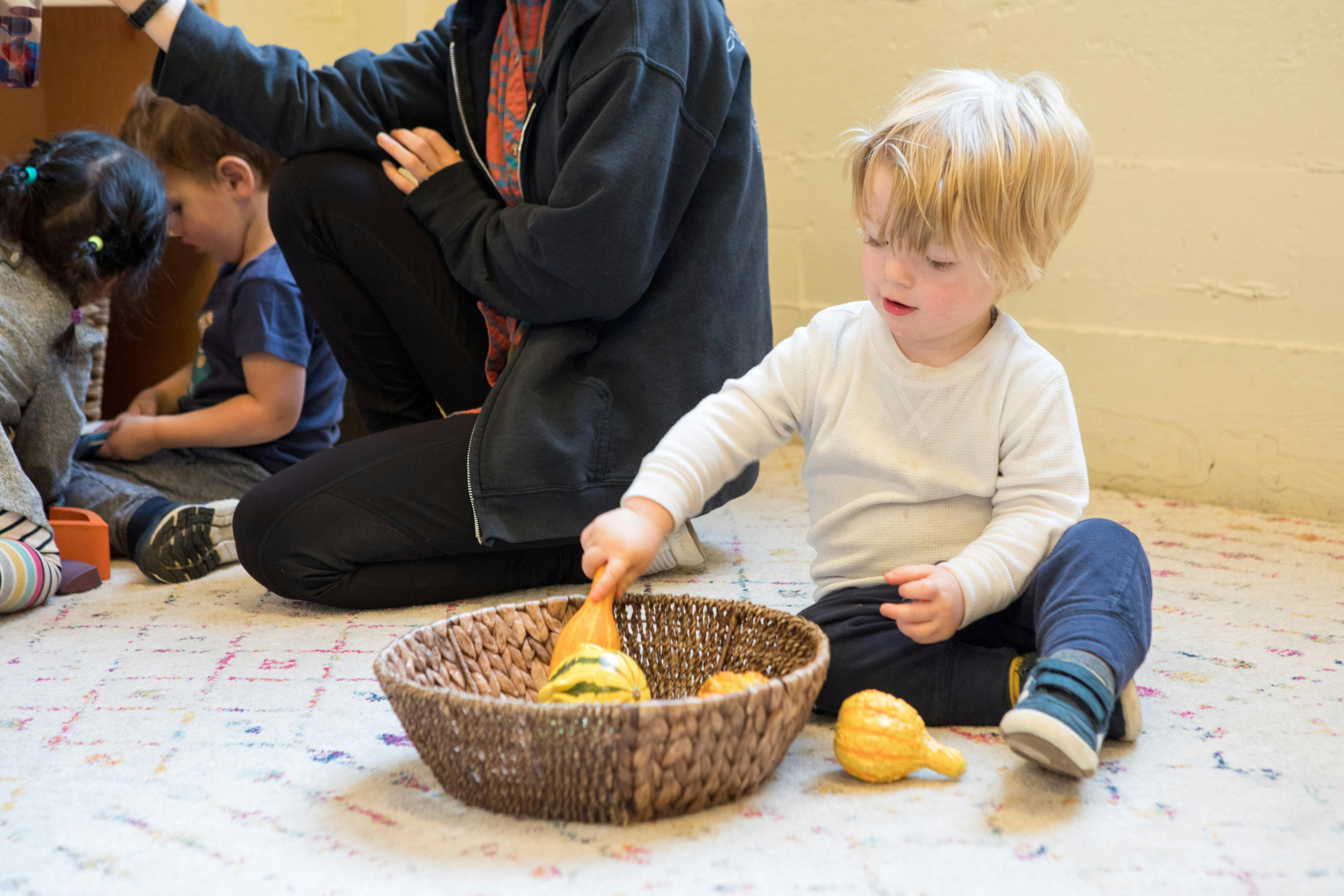 Child playing with gourds in a basket