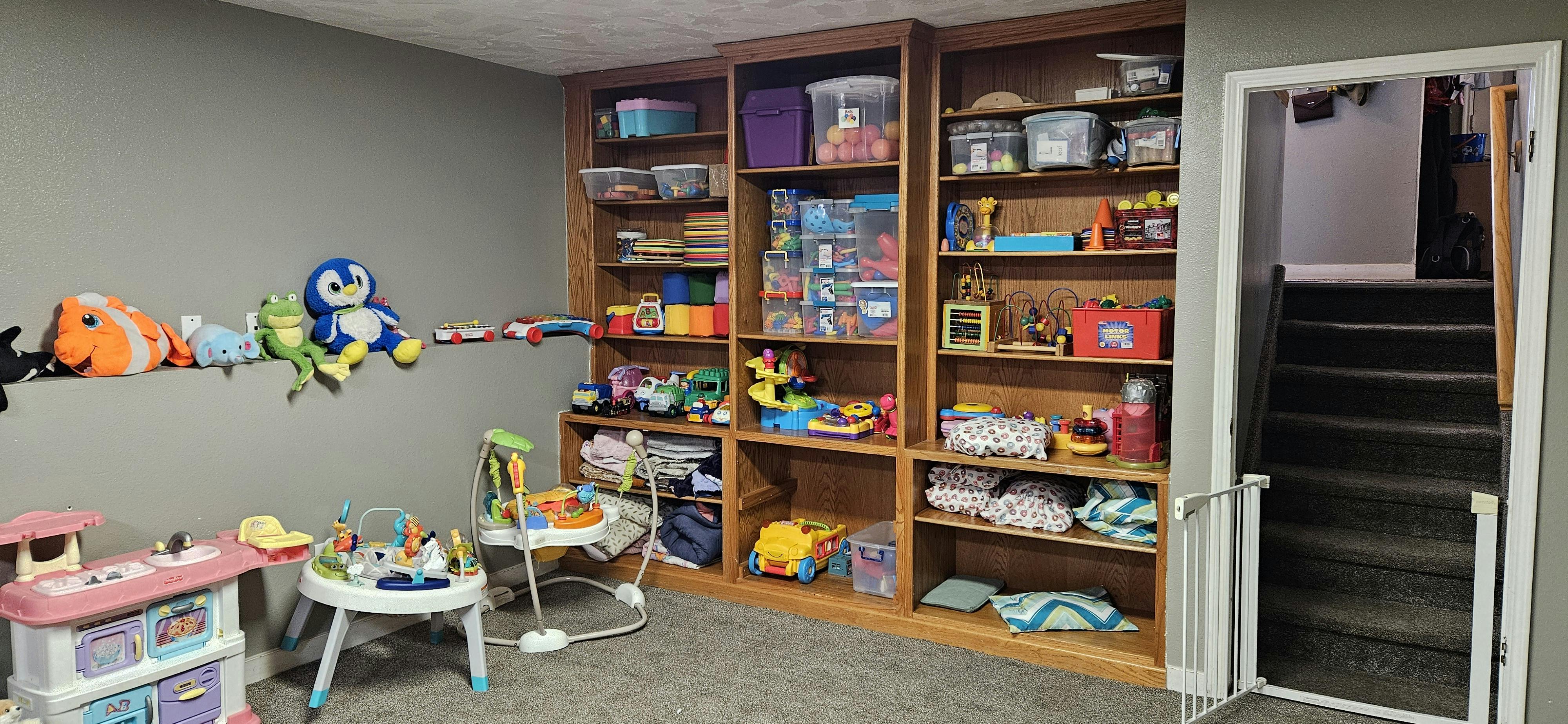 Playroom with shelves of toys and stuffed animals on a wall ledge