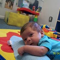 Infant lying on stomach on a mat