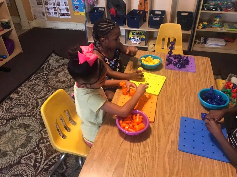 Children playing with colorful pegboards and pegs at a table