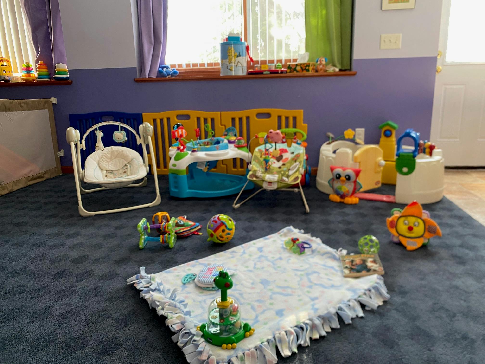 Baby play area with various toys, bouncer, and activity center