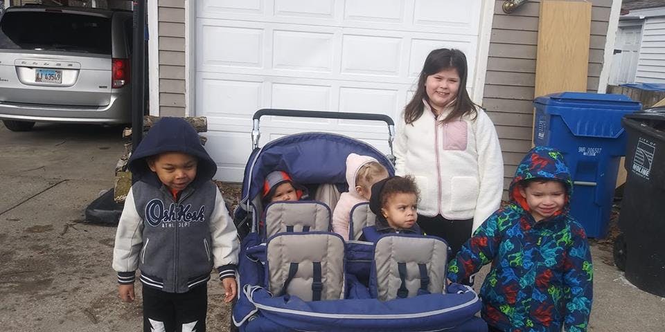 Four children and two babies in a stroller outdoors