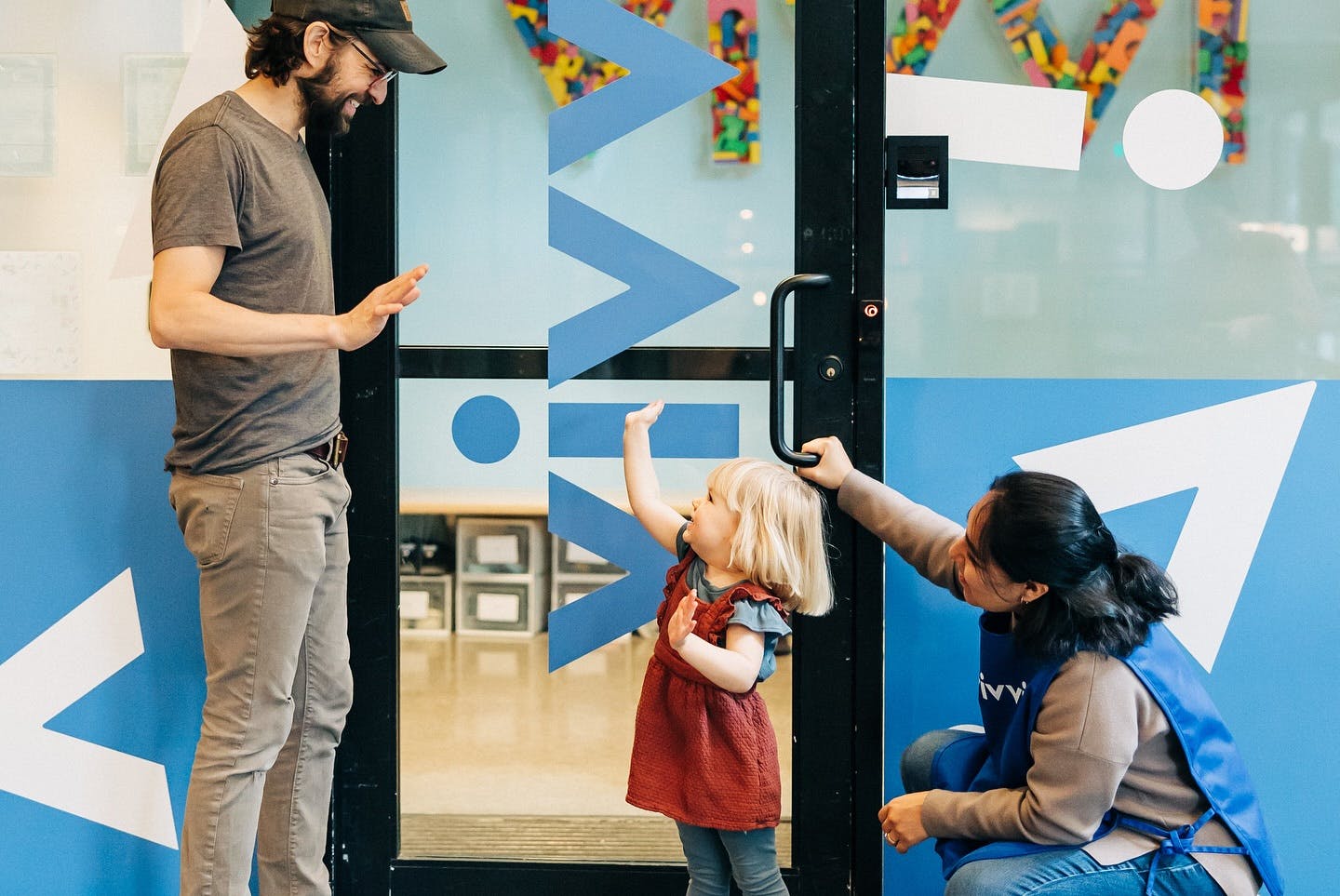 Person and child interacting with another person at a doorway