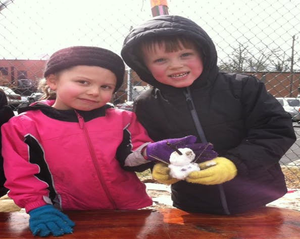 Two children standing, one holding a small white object