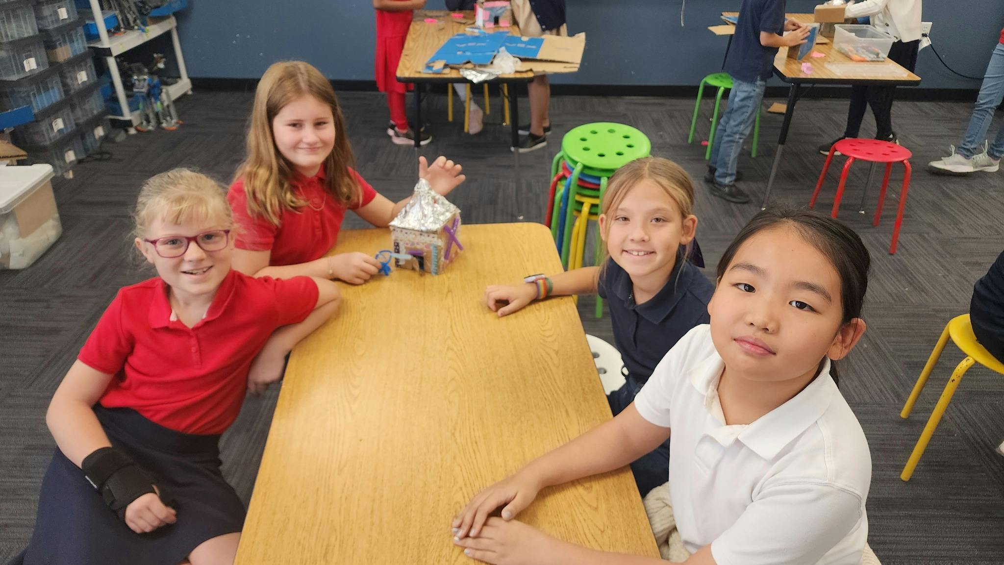 Four children sitting at a table in a classroom