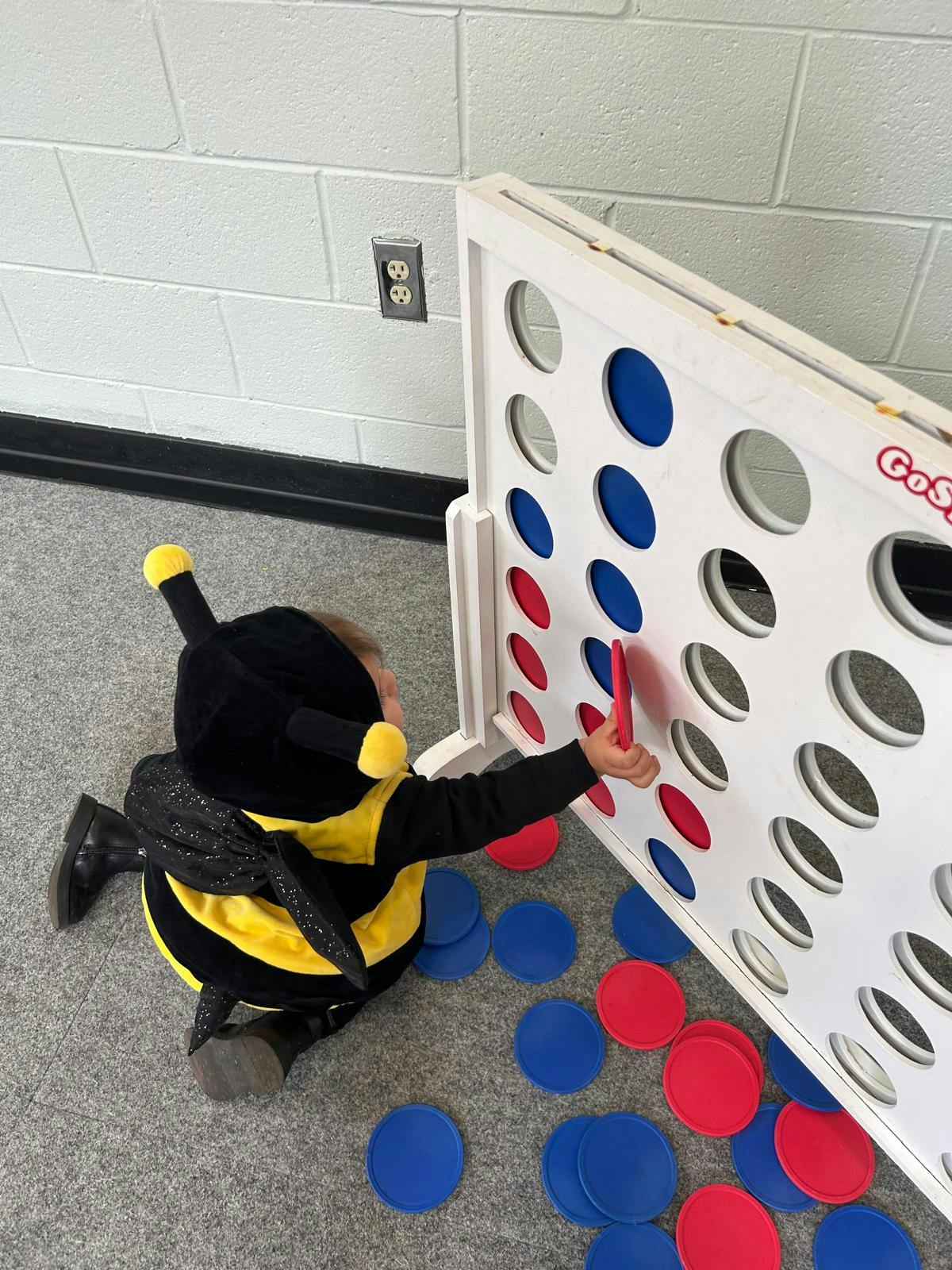 Child in a bee costume playing a vertical disc game
