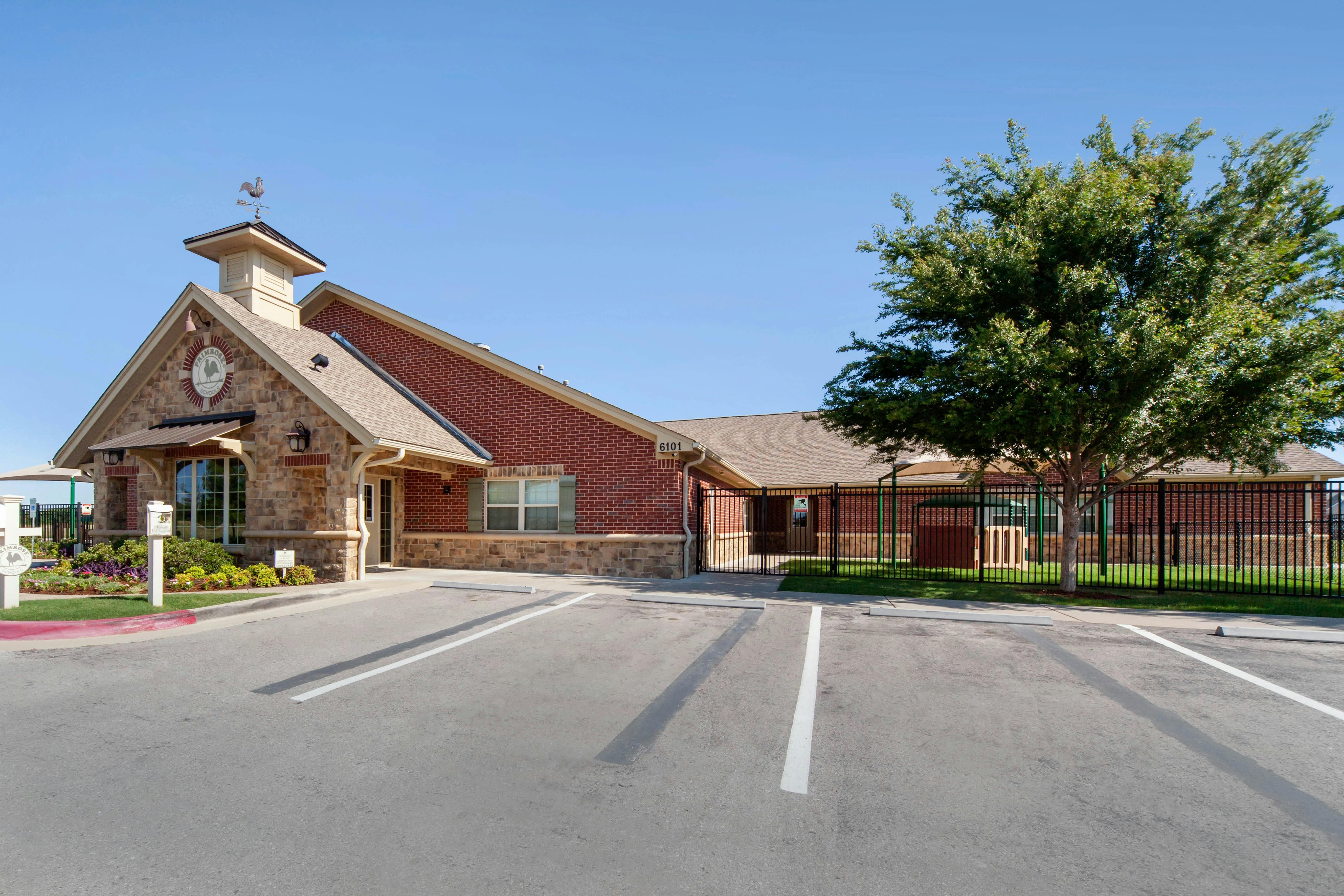 Brick building with stone accents, a sign that says Primrose School, and a parking lot