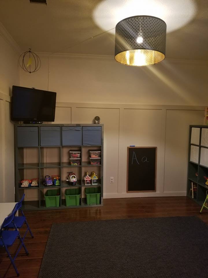 Playroom with toy shelves, television, and chalkboard