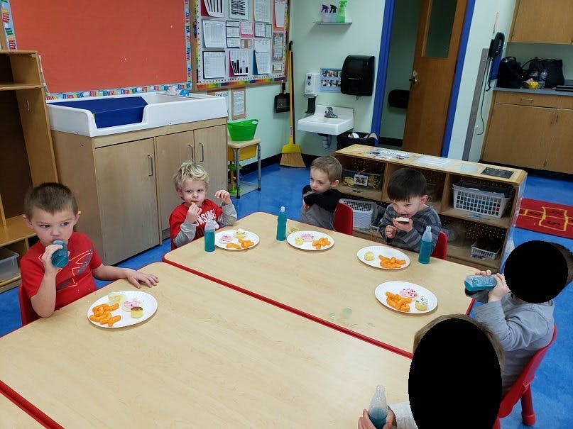 Children eating snacks at a table in a classroom