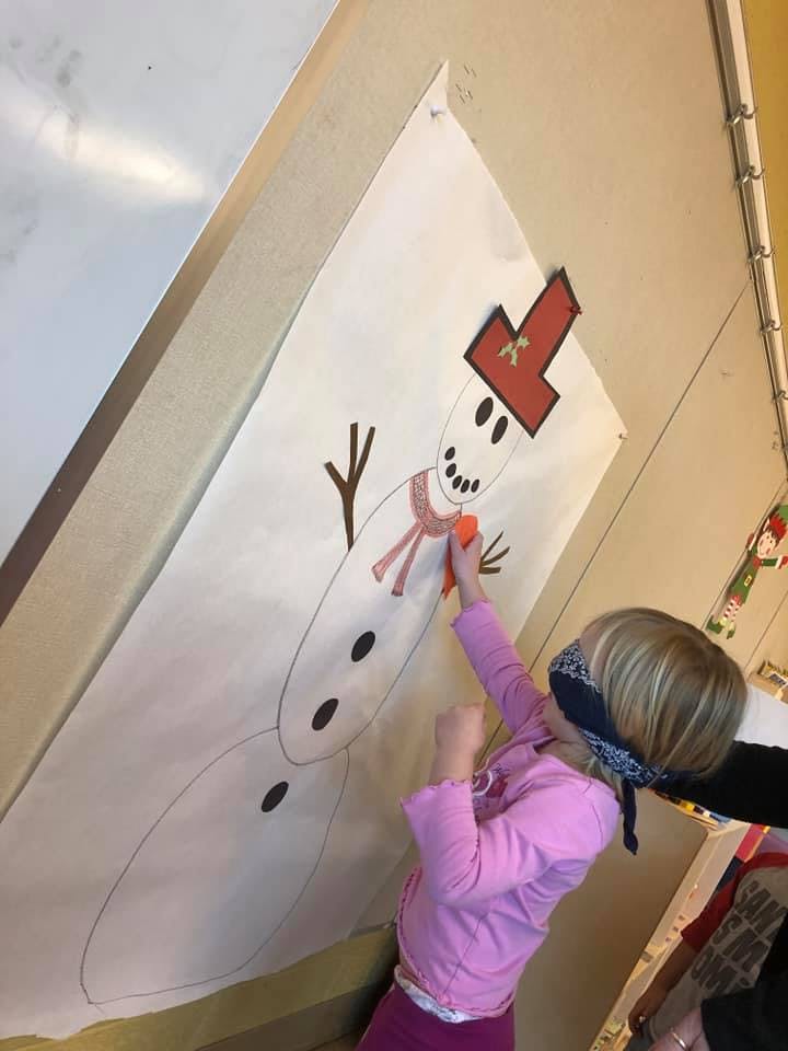 Blindfolded child playing pin the nose on the snowman