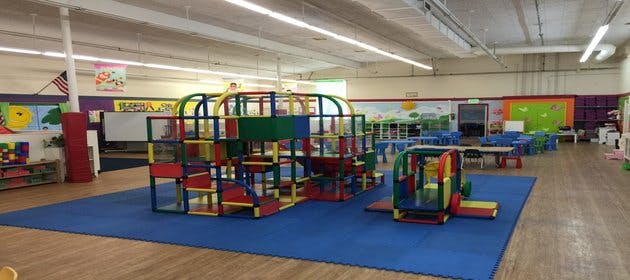 Indoor playground with colorful climbing structure and blue mat