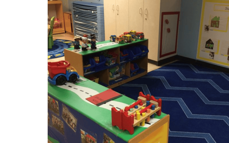 Classroom with toy figures, trucks, and a wooden pounding toy