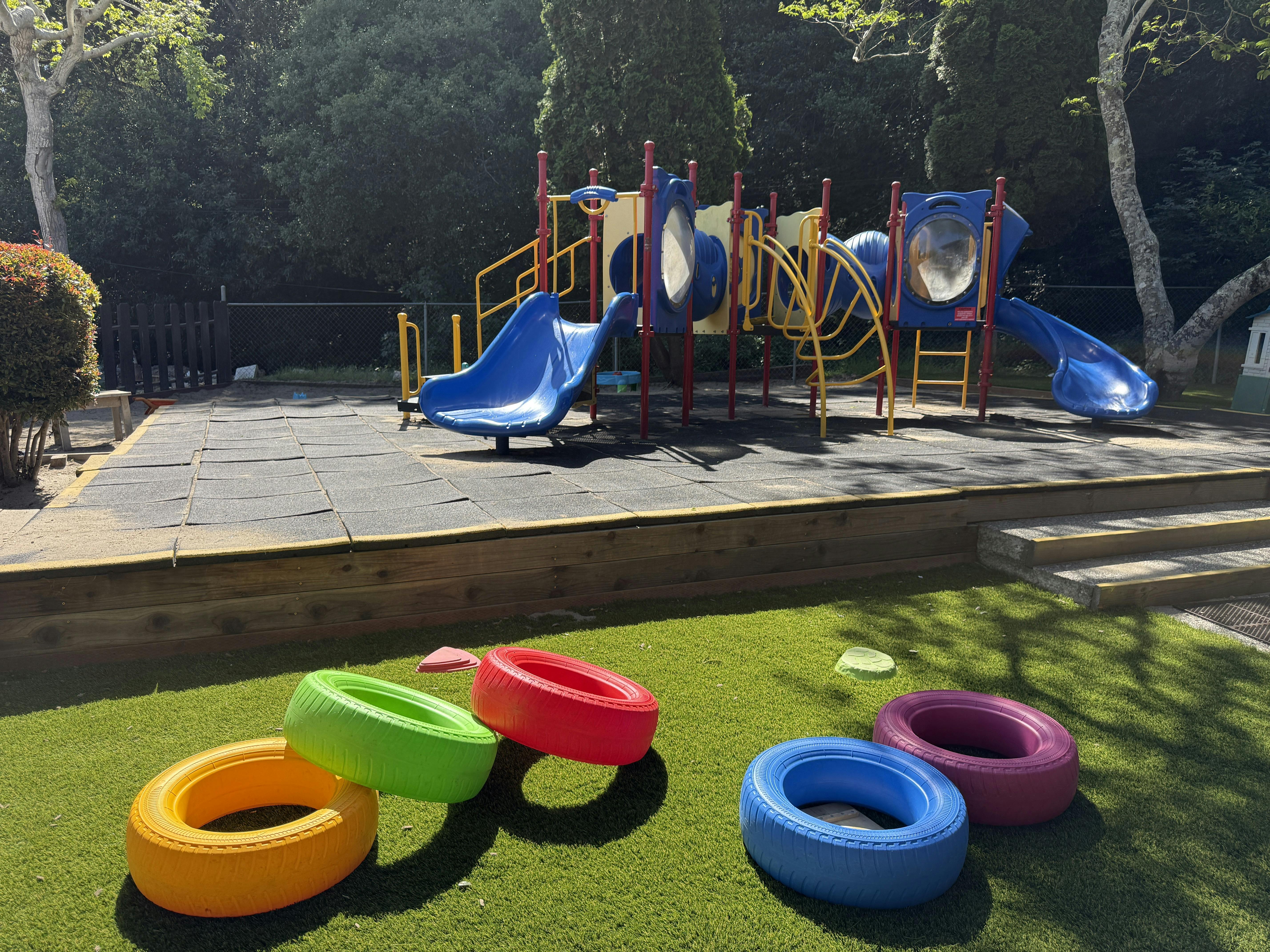 Playground with slides and tunnels, colorful tires on artificial grass