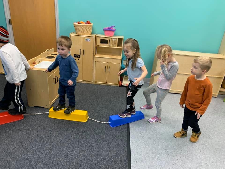 Children playing on balance beams in a classroom