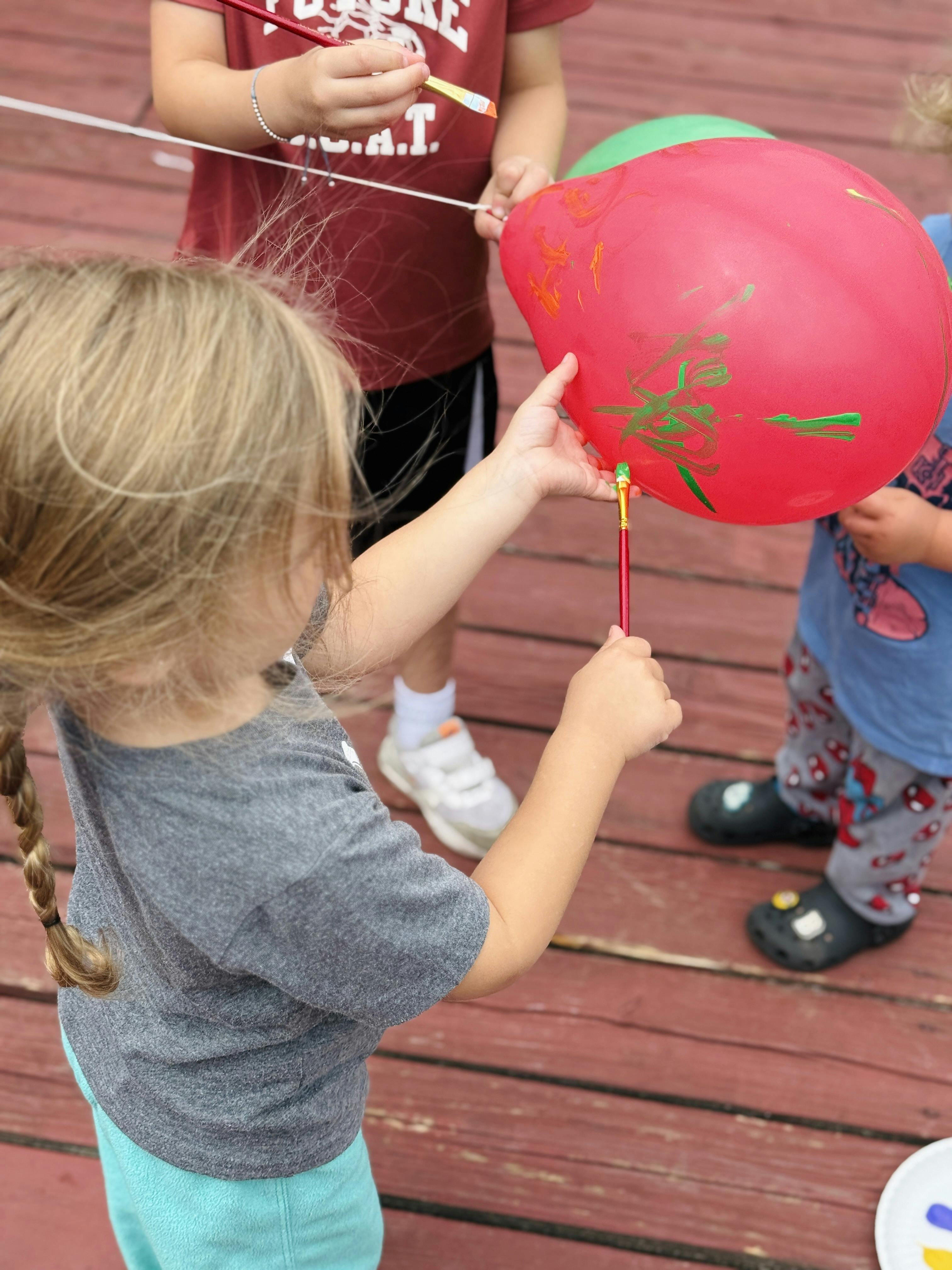 Children painting on red balloons