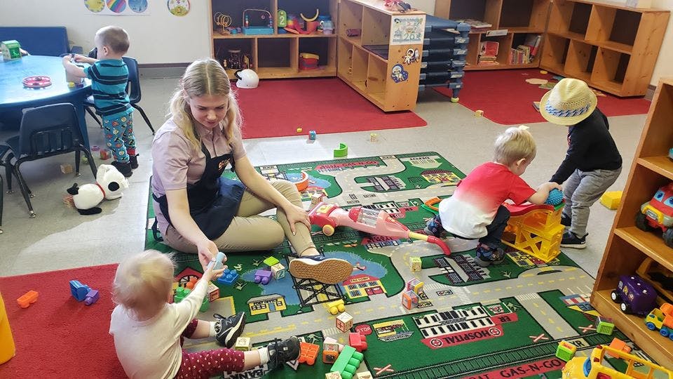 Adult and children playing with toys on a rug