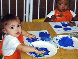 Two children finger painting with blue paint