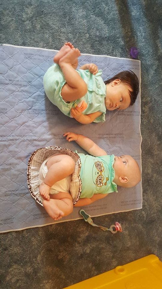 Two babies lying on a mat