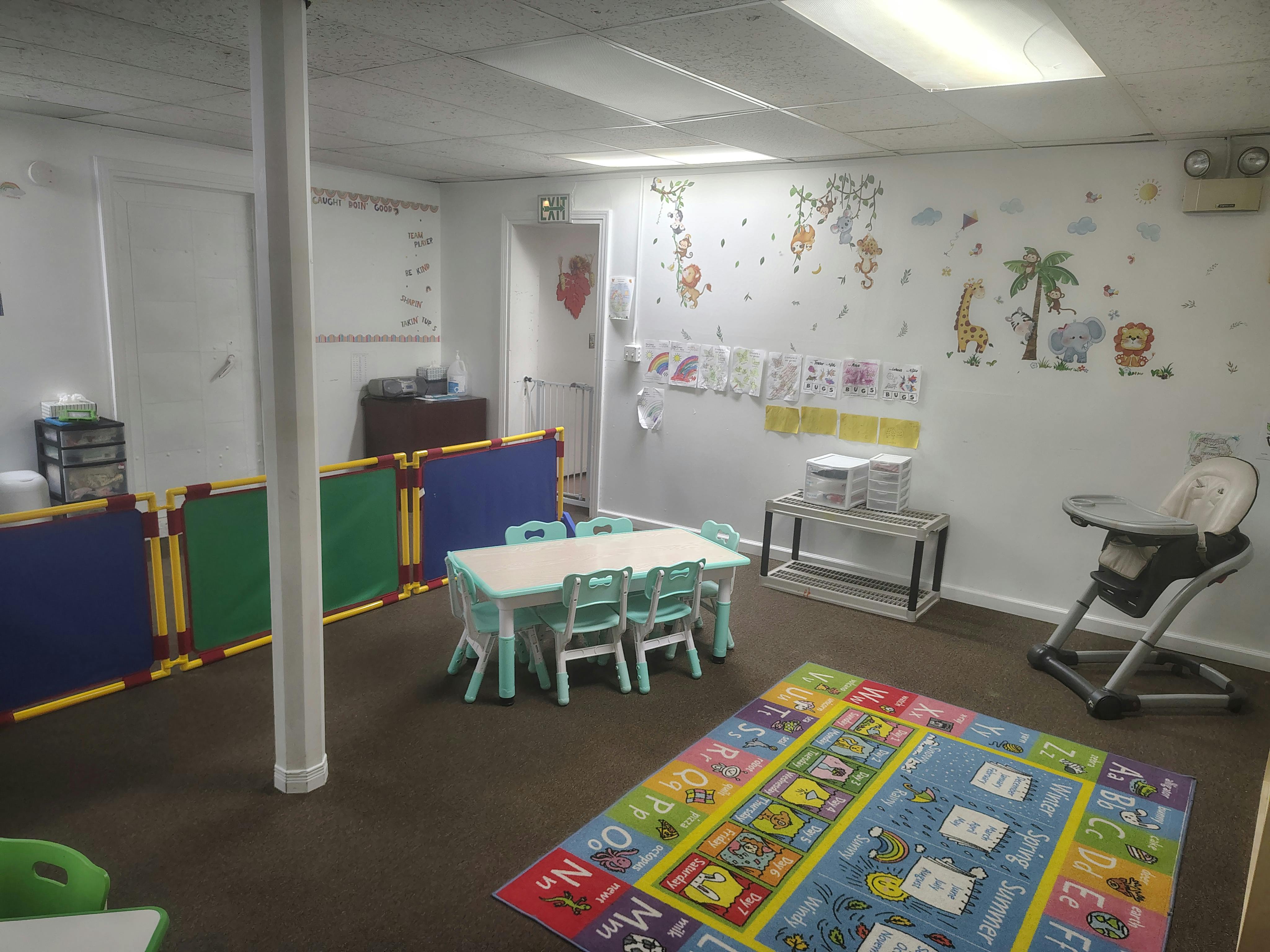 Childcare room with small table, chairs, and alphabet floor mat