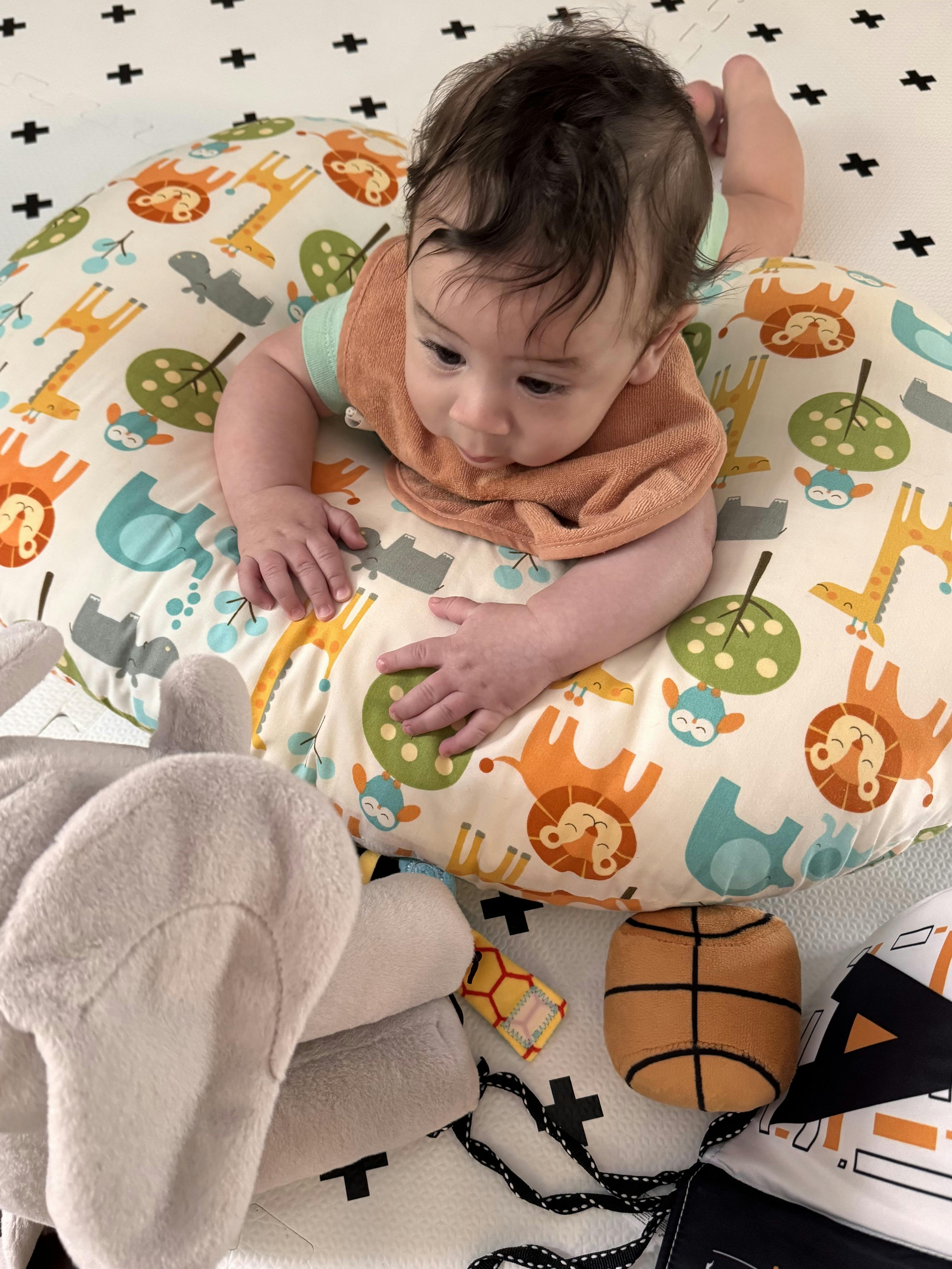 Child lying on stomach on a jungle animal pillow, looking down