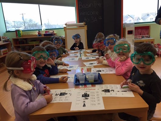 Children wearing safety goggles at a table in a classroom