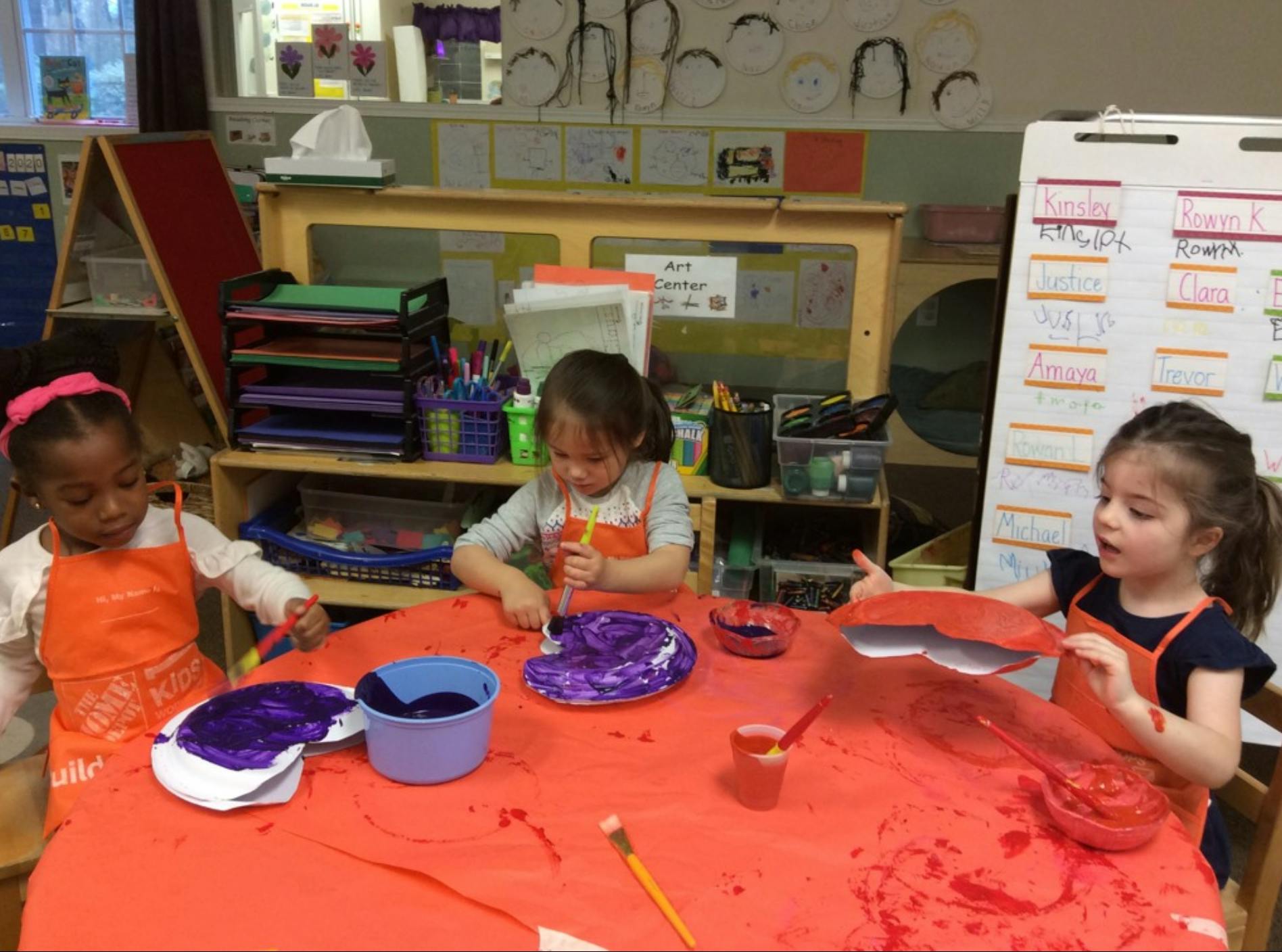 Three children painting in a classroom
