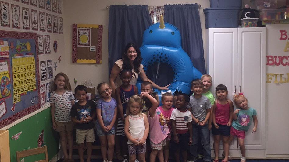 Adult and children posing in a room with a blue inflatable narwhal