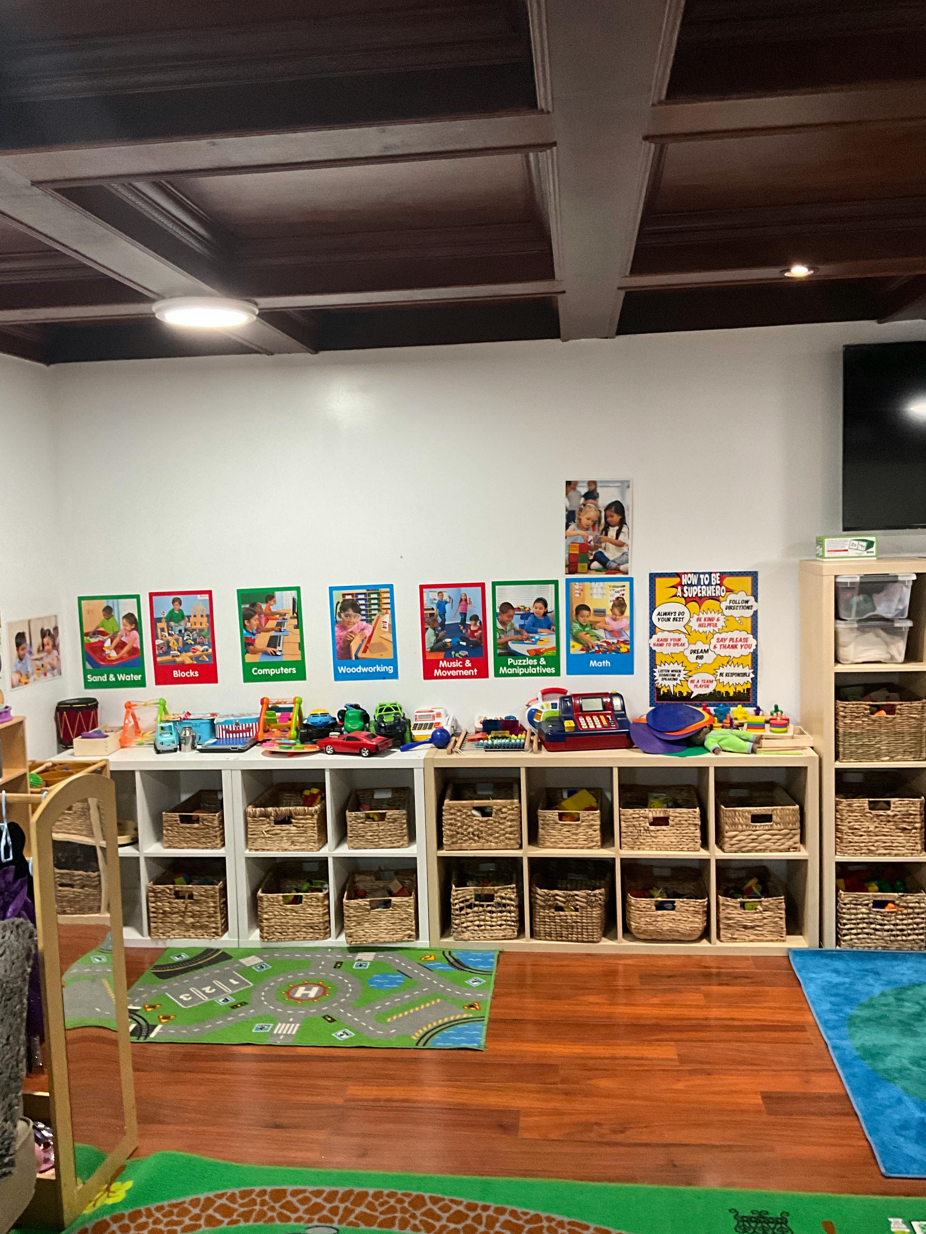 Classroom with shelves of baskets, posters on the wall, and play mats on the floor
