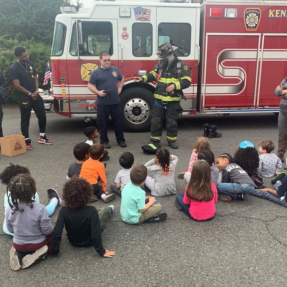 Firefighter in uniform talking to a group of children sitting on the ground