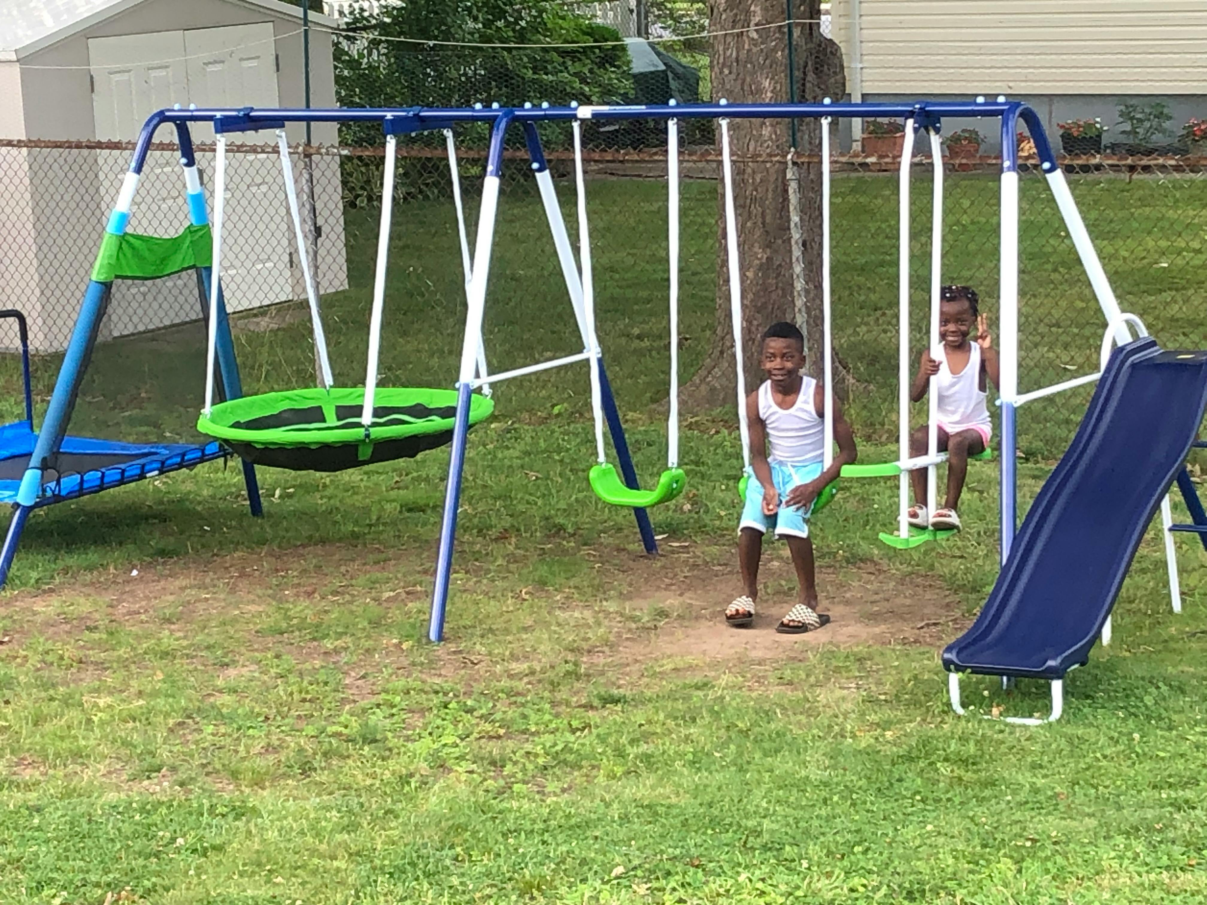 Two children on a swing set in a grassy yard