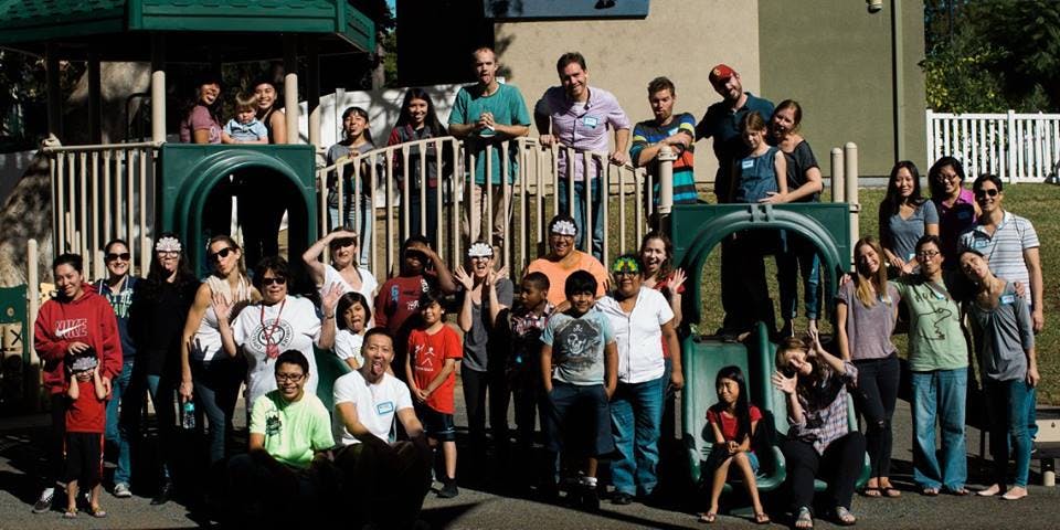 Group of people and children posing on and around playground equipment