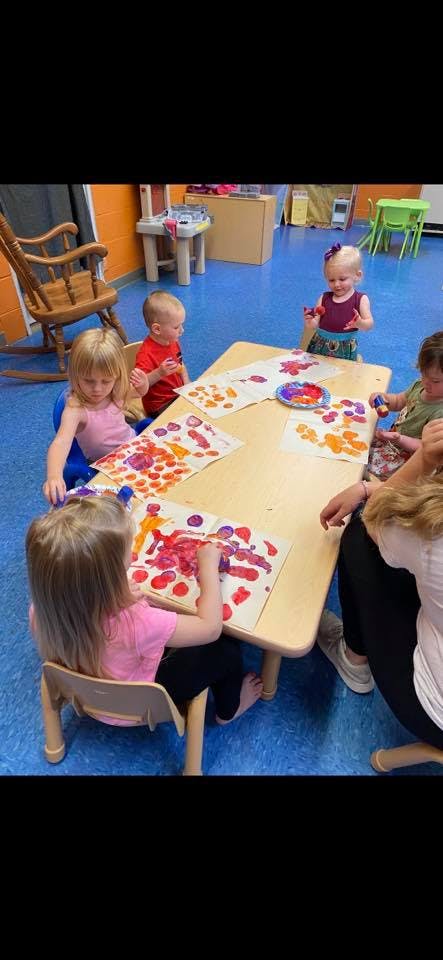Children painting at a table in a classroom