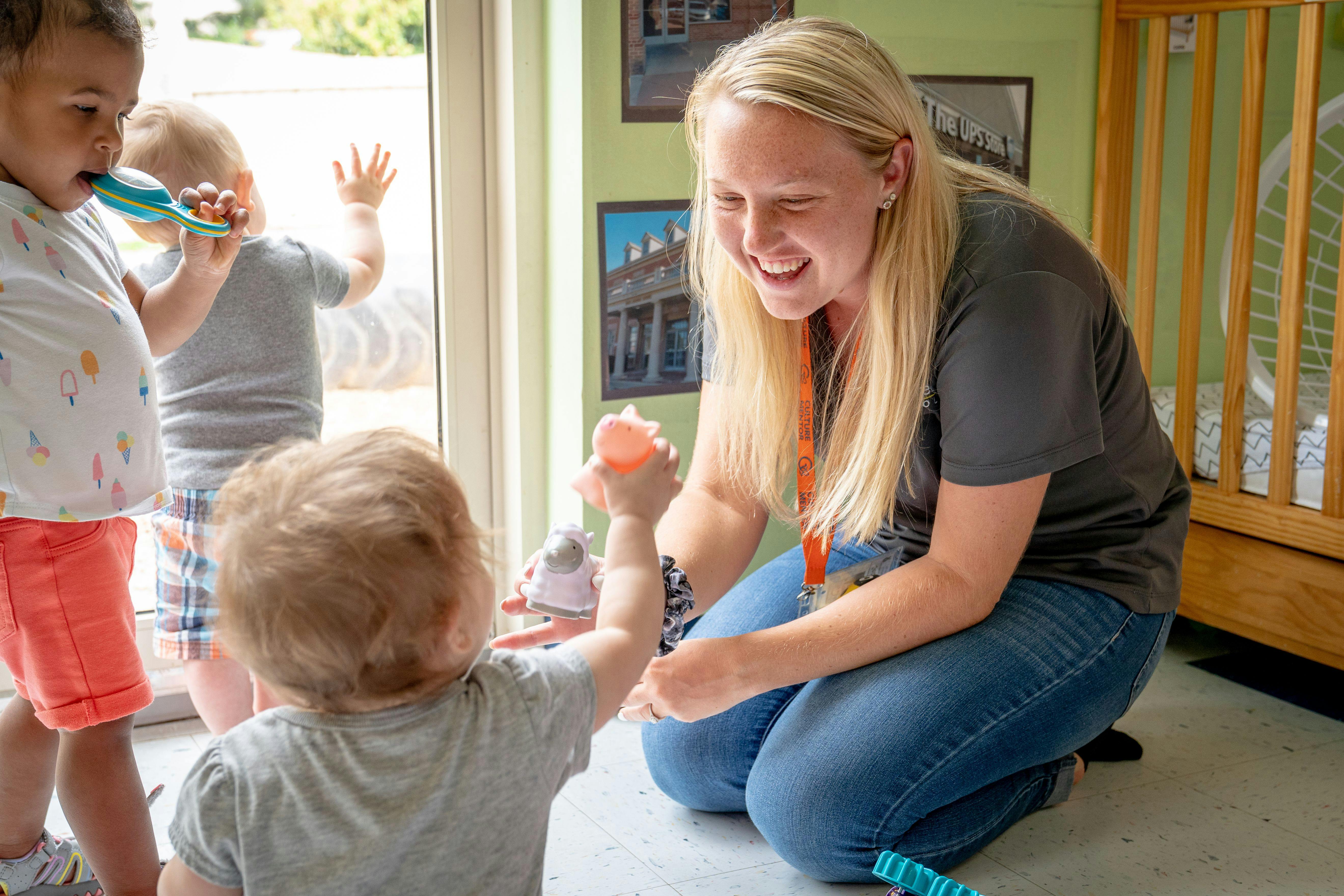 Adult kneeling and playing with children in a room
