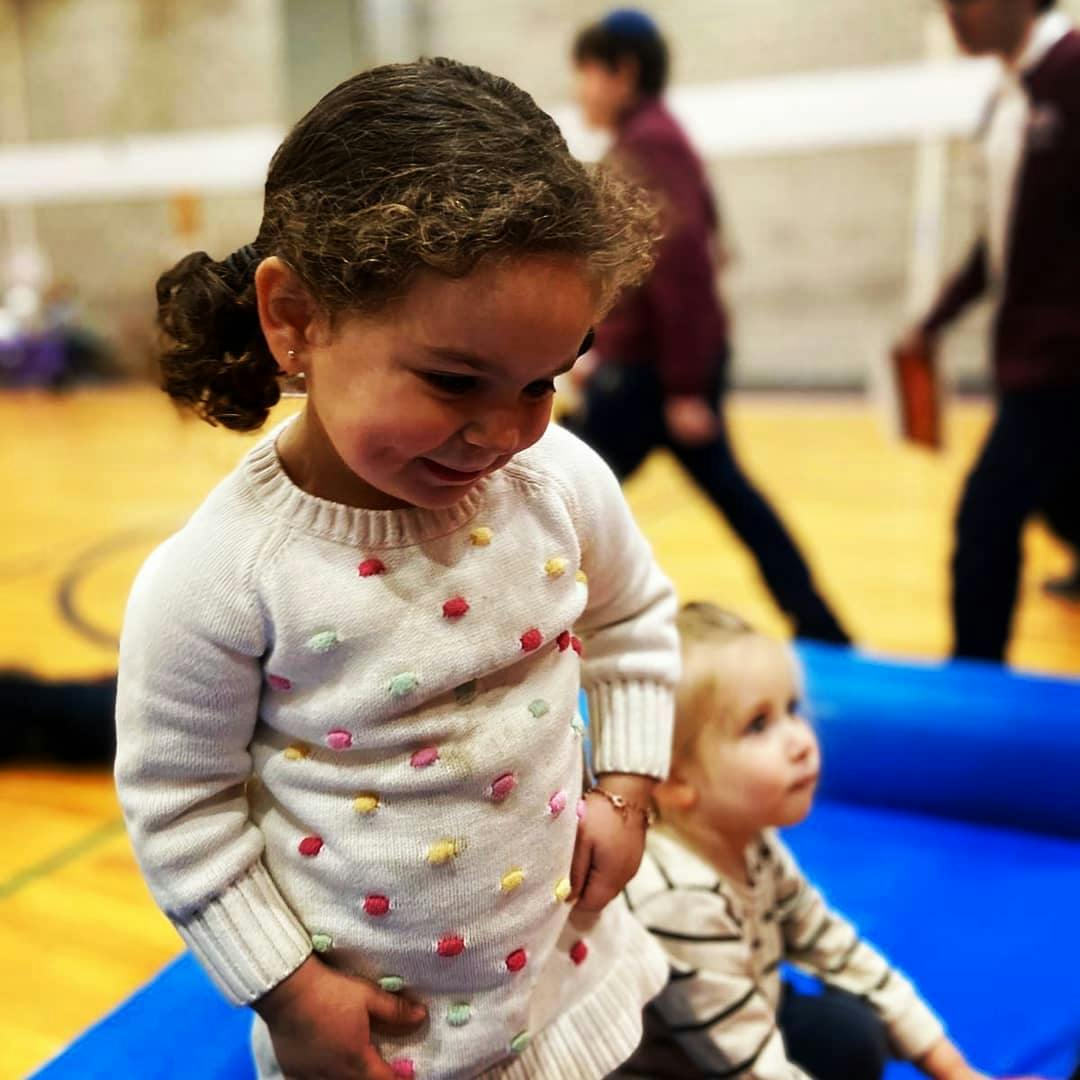 Child in a white sweater with colorful dots looking down