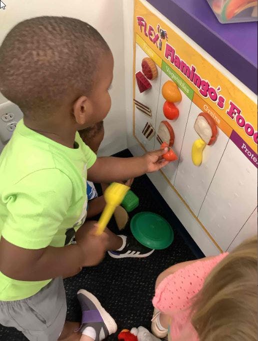 Child playing with a food-themed activity board